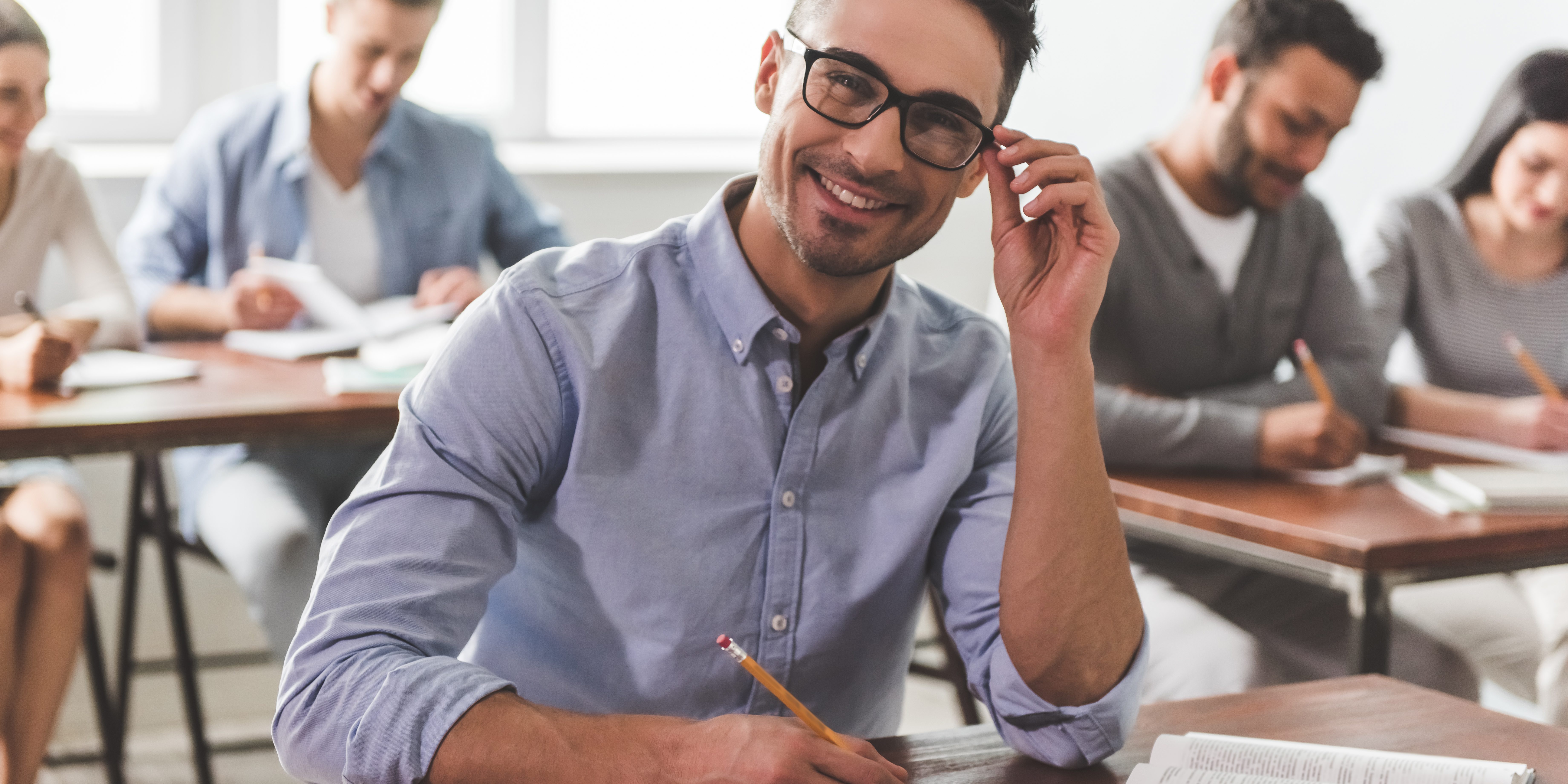 Guy is looking at camera and smiling while making notes.