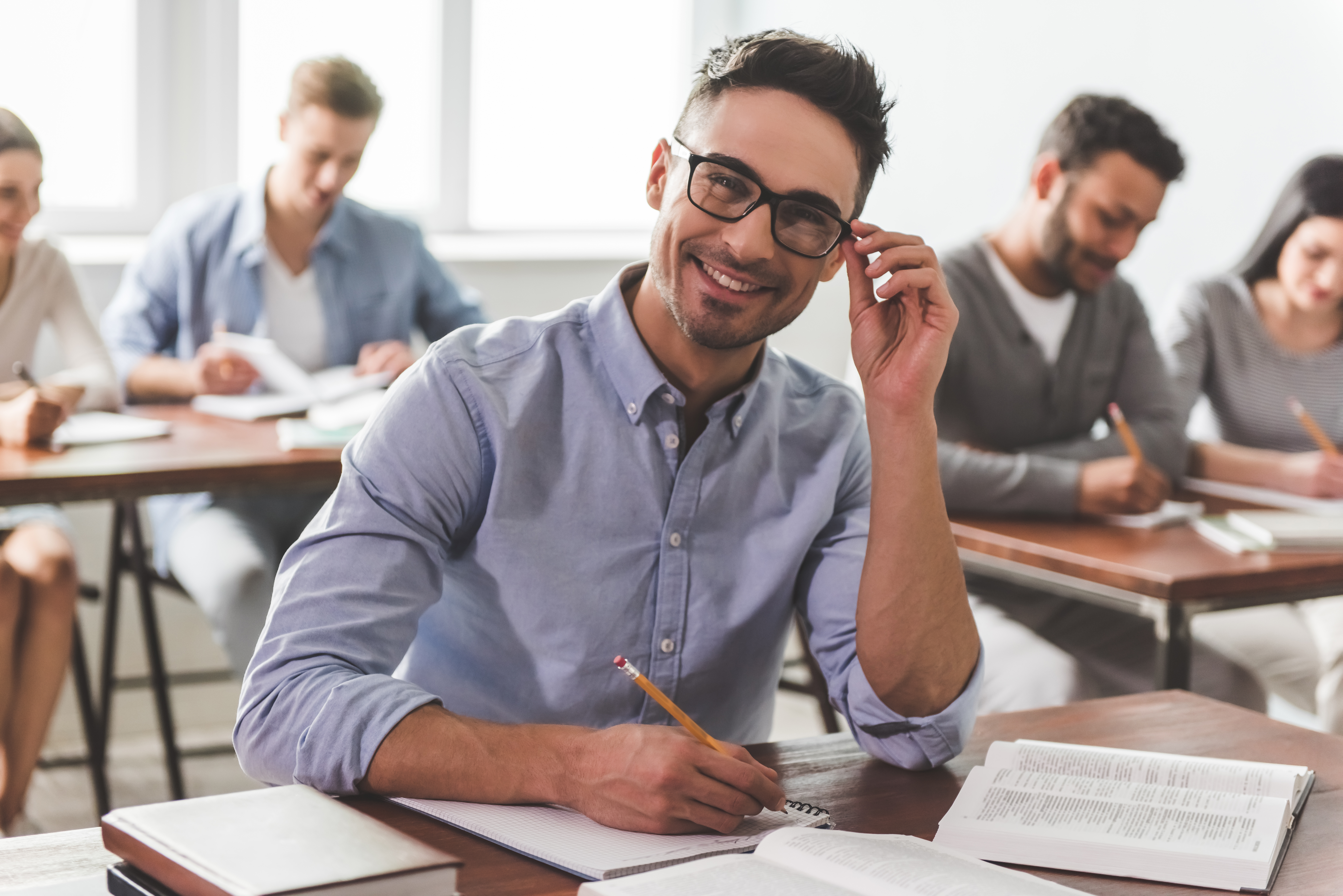 Guy is looking at camera and smiling while making notes.