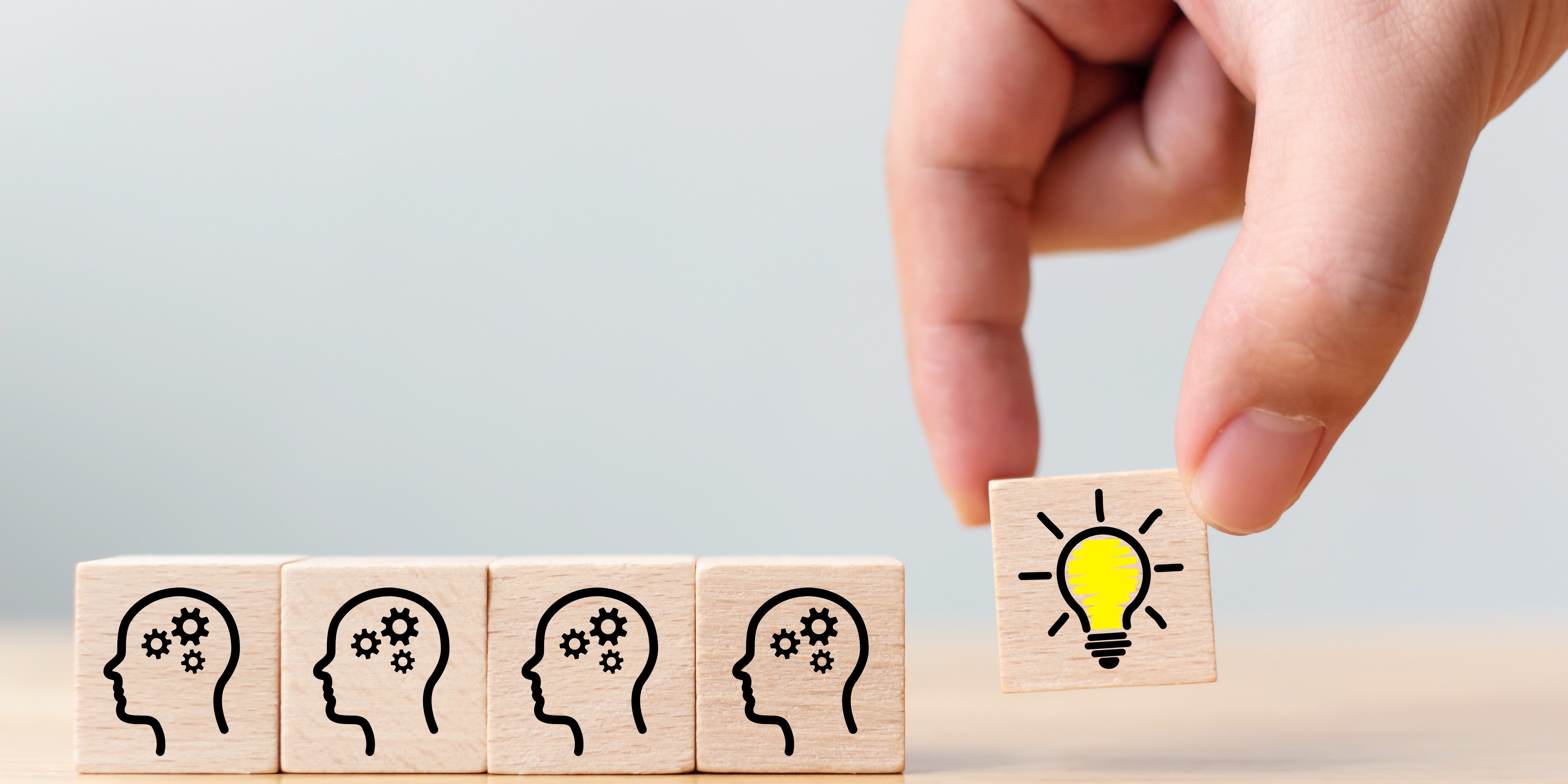 Concept creative idea and innovation. Hand picked wooden cube block with head human symbol and light bulb icon