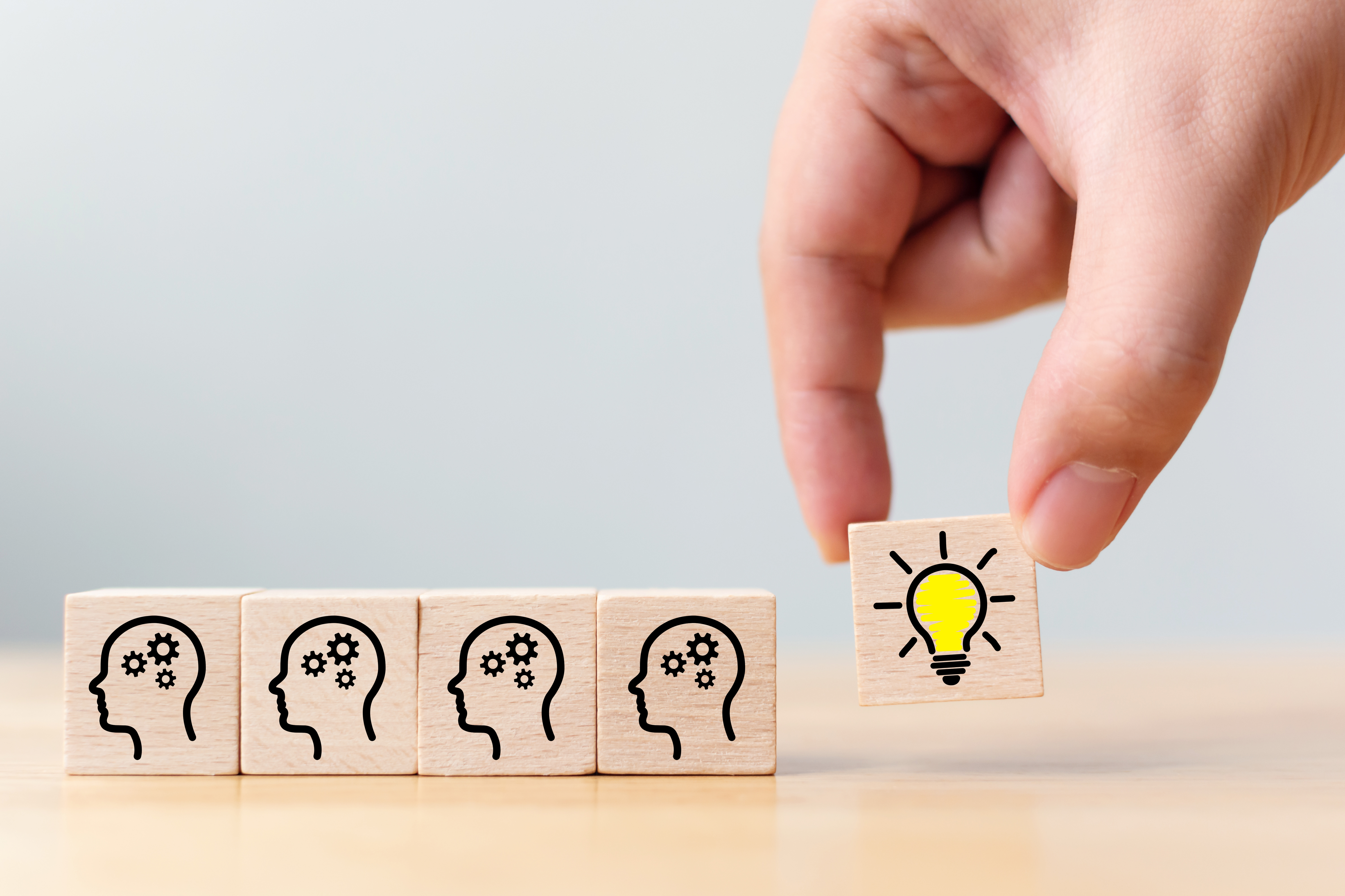 Concept creative idea and innovation. Hand picked wooden cube block with head human symbol and light bulb icon